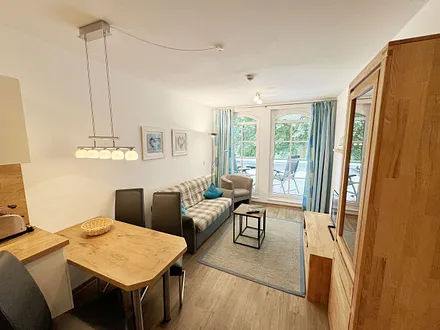 Wohnbereich mit gemütlicher Couch (Aufbettung für die 3. Person 1,30 m x 1,95 m), Sessel, Couchtisch, Leselampe, kleine Anrichte mit LCD-TV sowie ein Radio mit CD 