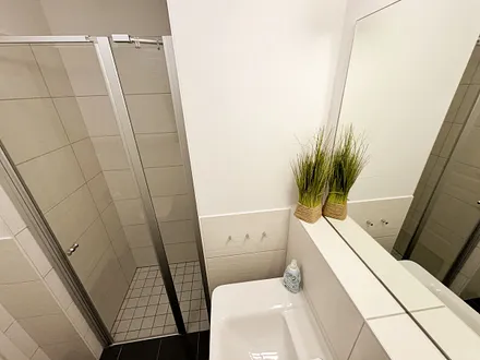 Badezimmer mit ebenerdiger Klarglasdusche, Waschtisch, WC, Fön und Handtuchheizkörper 