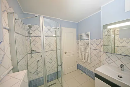 Badezimmer mit ebenerdiger Echtglasdusche, WC, Handtuchtrockner sowie Badmöbel