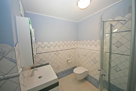 Badezimmer mit ebenerdiger Echtglasdusche, WC, Handtuchtrockner sowie Badmöbel