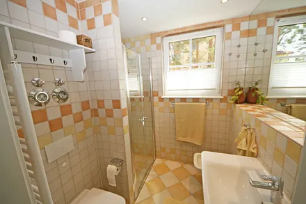 Badezimmer mit ebenerdiger Dusche, WC, großem Waschbecken, Fön, großzügigem Wandspiegel und ein Bidet