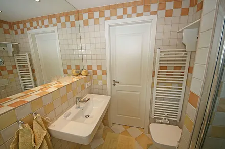 Badezimmer mit ebenerdiger Dusche, WC, großem Waschbecken, Fön, großzügigem Wandspiegel und ein Bidet