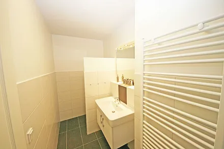 Badezimmer mit ebenerdiger Dusche, Waschtisch, WC, beheizbarer Handtuchtrockner und Fön