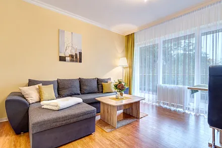 Wohnzimmer mit Schlafcouch, Essplatz, Flat-TV, Stereoanlage und Balkon zur Südseite