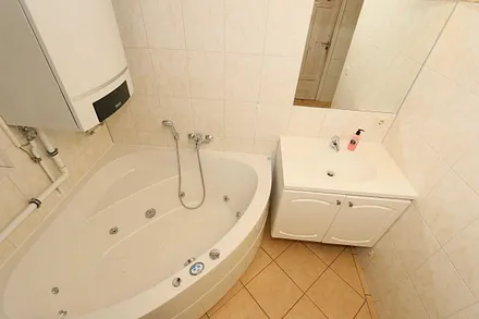 Badezimmer mit ebenerdiger Dusche, Waschplatz, WC, Fön, Kosmetikspiegel, Waschmaschine, Sauna und Badewanne mit Whirlpool