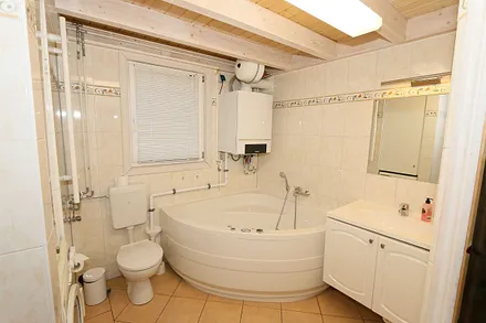 Badezimmer mit ebenerdiger Dusche, Waschplatz, WC, Fön, Kosmetikspiegel, Waschmaschine, Sauna und Badewanne mit Whirlpool