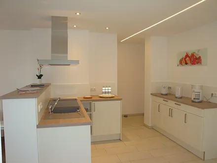 Küche mit Geschirrrspüler, Ablufthaube, Ceranherd, Kühlschrank mit Gefrierfach, Toaster, Kaffeemaschine und Wasserkocher