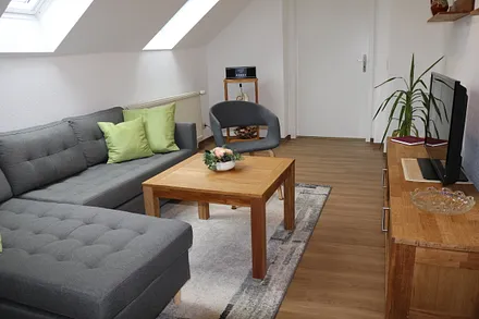 Wohnzimmer mit gemütlicher Couch, Flachbildfernseher und Radio