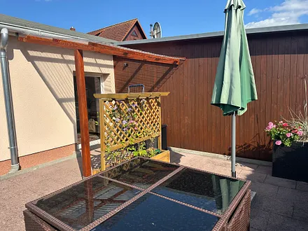Grosse Terrasse mit Tisch und mobilen Sonnenschirm