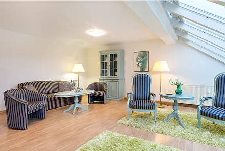 Die Fenster sind mit Plissees ausgestattet. Das Wohnzimmer schaut nach Nordosten auf die Ostsee. Die Couch hat keine Schlaffunktion.