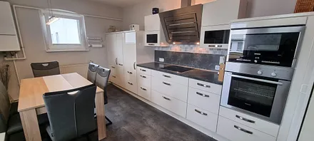 Die moderne Einbauküche ist voll ausgestattete mit Cerankochfeld, Backofen,  Mikrowelle,  Küh-u. Gefrierschrank,  Abzugshaube, hohen Spüle mit Geschirrspülmaschine,  Tisch mit 6 Stühlen. 