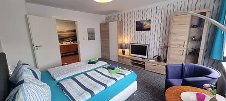 1. Schlafzimmer mit kleiner Anbauwand, Kleiderschrank, Sat-TV,  2 Clubsessel und Tisch, Verducklungsvorhang 