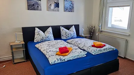 Das Schlafzimmer ist mit Auslegeware verlegt und ist ausgestattet mit  einem Boxspringbett, Nachttischen, Leseleuchten, einem großen Kleiderschrank,  einer Schlafcouch, 2 Stühlen und kleinem Tisch