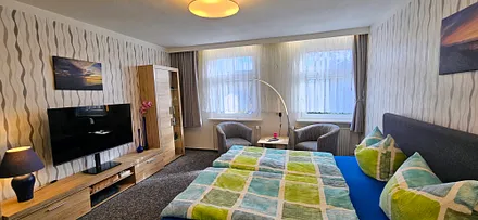 Schlafzimmer mit Doppelbett (180×200cm),Anbauwand mit TV, Tisch und 2 Clubsessel ,Leselampe, Verducklungsvorhang 