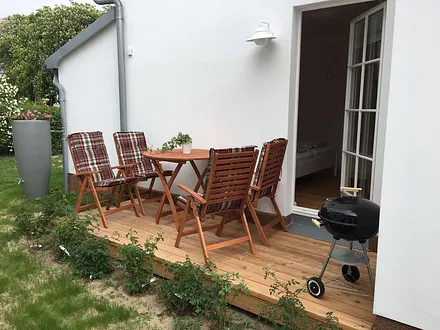Terrasse mit Sitzmöbeln, Grill, Wildrosenhecke