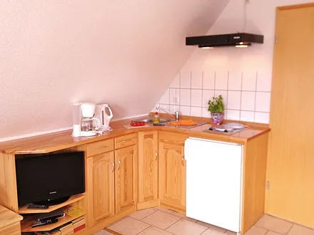 Küchenzeile (2-Platten-Herd. Kaffeemaschine, Wasserkocher, Toaster) mit Entertainmentbereich (Flachbild-TV, Bücherecke)