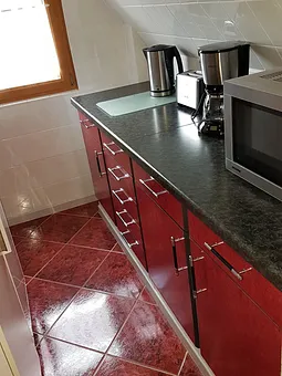 Küchenzeile mit Microwelle, Kaffeemaschine, Toaster und Wasserkocher.