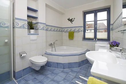 Das Badezimmer in maritimem Design verfügt über eine große Eckbadewanne.