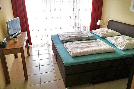 Schlafzimmer mit Doppelbett-Boxspringmatratzen und TV