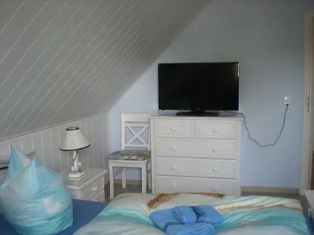 Schlafzimmer mit Doppelbett und TV