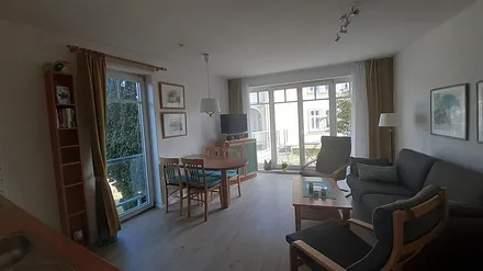 Heller Wohnbereich mit bequemen Möbeln, Smart-TV u. hochwertiger Micro-Stereoanlage. Das begrünte Tiefgaragendach vor der nach Süd. ausgerichteten Terrasse u. der Garten sind ebenfalls nutzbar.