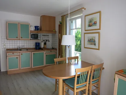 In den Wohnbereich harmonisch integriert ist eine komplett eingerichtete Küchenzeile. Durch das raumhohe Seitenfenster schaut man ins Grüne u. in den Frühjahrs- und Wintermonaten sogar auf das Meer.