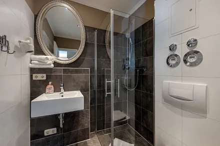 Das Bad hat WC, Fön und eine bodengleiche Glasdusche.