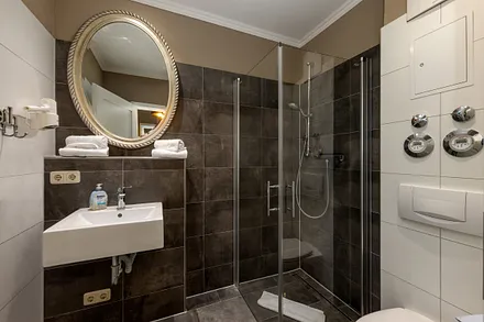 Das schöne Bad bietet Fön, bodengleiche Echtglasdusche, Handtuchtrockner und WC.