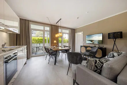 Hier der Blick in das Wohnzimmer mit TV, Küchenzeile und Austritt zum Balkon.