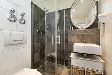 Das schicke Bad bietet Ihnen eine bodengleiche Echtglasdusche, Fön, beleucheten Kosmetikspiegel und WC.