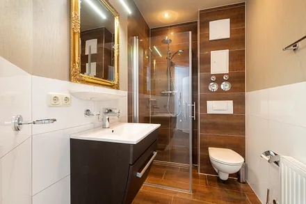 Das schicke Bad hat eine bodengleiche Echtglasdusche, Fön und WC.