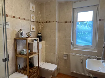 Im großen raumhoch gefliesten Bad befinden sich das WC, Dusche und der Waschtisch. Ein Fön befindet sich im Badschrank. 