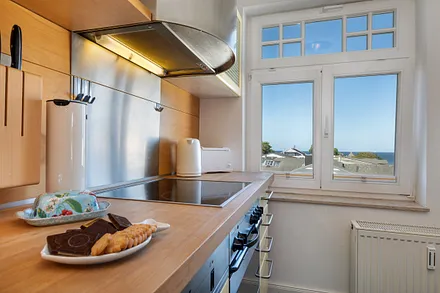 Geschirr, Besteck und Küchengeräte sind überwiegend von namhaften Marken. Auch im Küchenfenster sehen Sie das Meer.