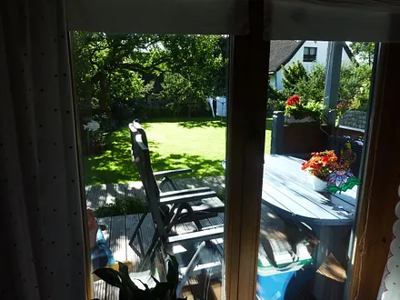 Blick aus dem Wohnzimmer auf die Terrasse und den Garten