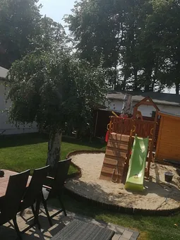 Garten mit Spielplatz, Sitzecke und ganz rechts zu sehen ist die Außensauna