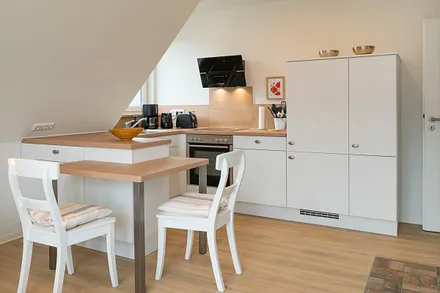 Küche mit Geschirrspüler, Cerankochfeld, Backofen, Kühlschrank mit Tiefkühlfach und Essplatz