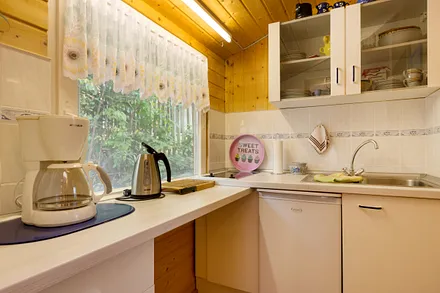 Die kleine Küchenzeile mit Kühlschrank, 2-Platten-Kochfeld, Kaffeemaschine, Wasserkocher und Toaster.