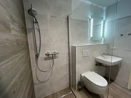 Bad- Blick von der Dusche, in Marmor-Beton-/ Holzoptik gefliest 