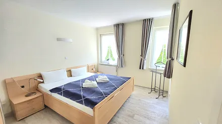 Schlafzimmer mit Doppelbett und Zugang zum Duschbad mit WC.