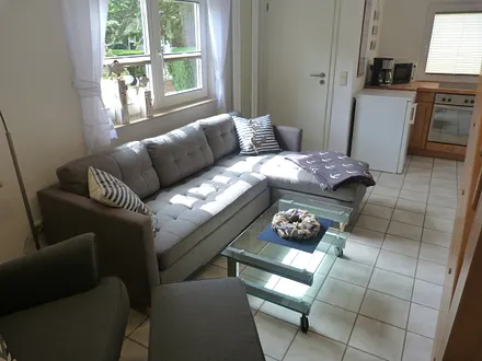 Das WZ ist mit einer Couch mit Récamiere und einem gemütlichen Ohrensessel mit Hocker und extra Leselampe ausgestattet.