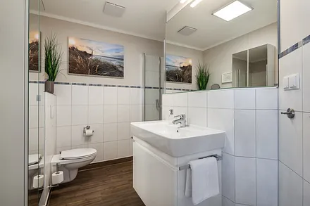 Bad mit bodengleicher Echtglasdusche, große Spiegelfront, Handtuchwärmer und viel Stauraum