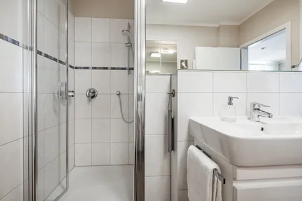 Badezimmer mit großer Dusche, Handtuchwärmer, Kosmetikspiegel und -tücher