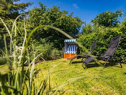 Eingezäunter Garten mit Strandkorb und Sonnenliegen