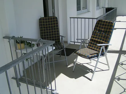 Vor Ihrer Wohnung stehen zwei Stühle auf dem Laubengang zum Genießen der Nachmittags- und Abendsonne.