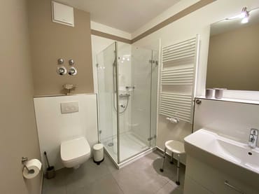 hochwertiges Badezimmer mit ebenerdiger Dusche, Waschplatz, WC, Handtuchheizkörper, Kosmetikspiegel und Fön