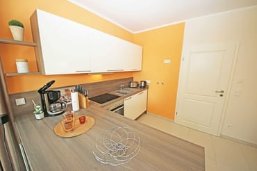 Küchenzeile mit Ceranfeld, Backofen, Geschirrspüler, Mikrowelle, Kühlschrank mit Gefrierfach, Kaffeemaschine, Wasserkocher, Toaster und diversen Küchenutensilien