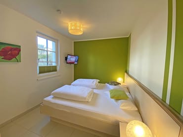 Schlafzimmer mit Doppelbett (2 x 0,90 m x 2,00 m), Nachttischkonsolen, Kleiderschrank und LCD-Flachbild-TV