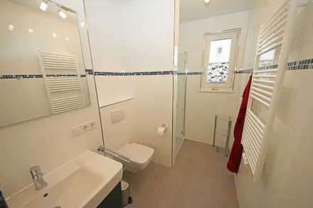 komfortables Badezimmer mit ebenerdiger Dusche, Waschtisch, Handtuchheizkörper, WC und Fön