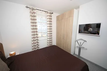 Schlafzimmer mit Boxspringbett (1,80 m x 2,00 m), Full HD Flachbildschirm, stillen Diener, zwei Nachtkonsolen, Kleiderschrankund Insektenschutzgitter