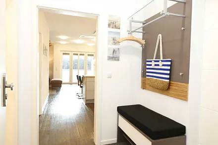 heller Flur mit Garderobe, Sitzgelegenheit und bodentiefem Spiegel